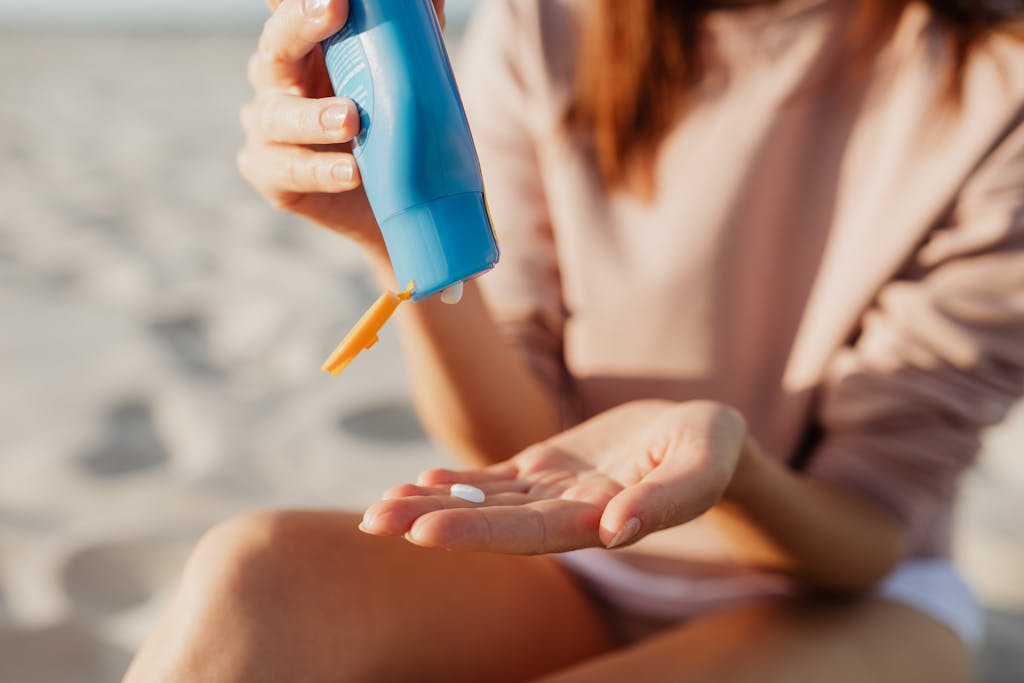 A person applies sunscreen at the beach on a sunny day.