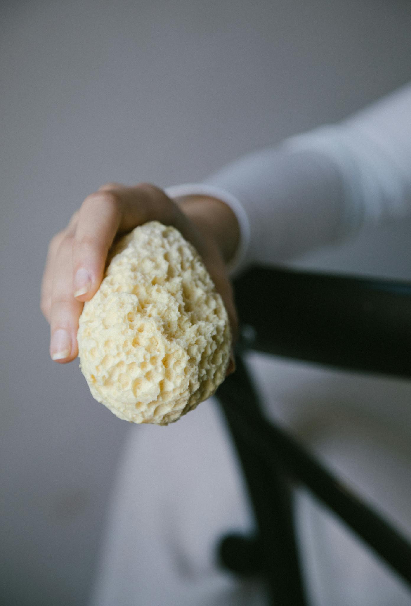 Close-up of a natural bath sponge being held, portraying eco-friendly skincare practices.