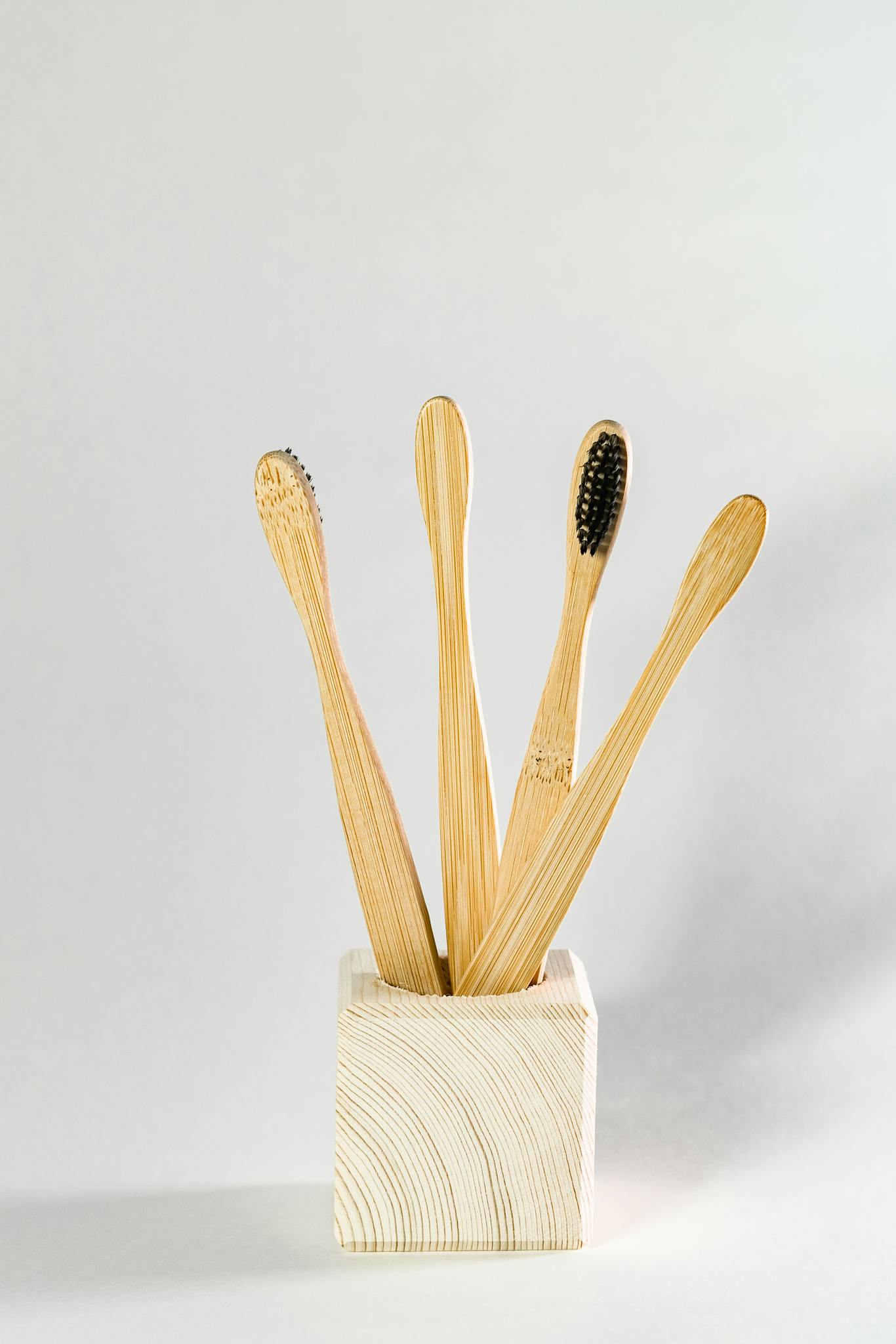 Minimalist still life of bamboo toothbrushes in a wooden holder for sustainable living.