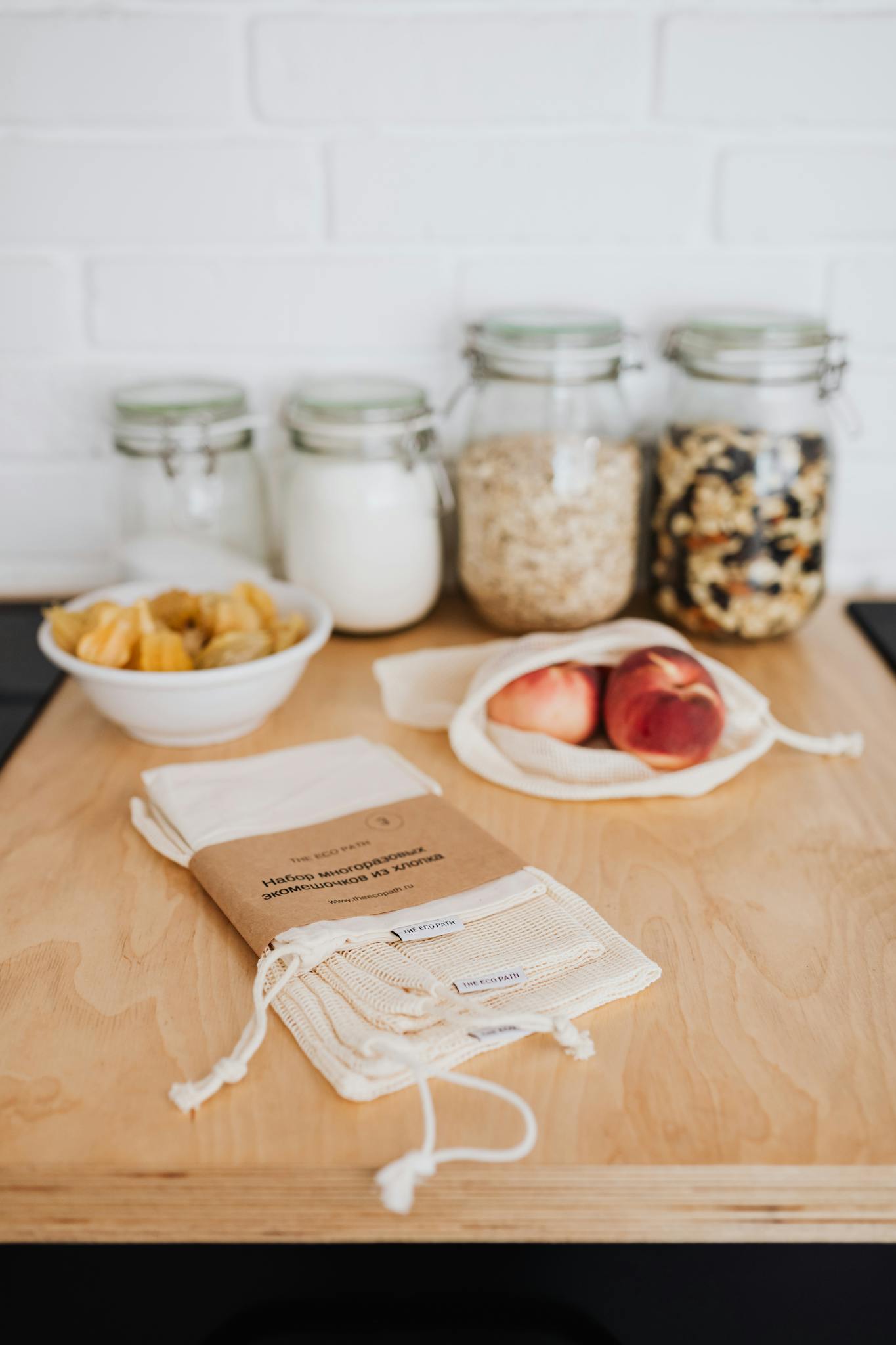 Sustainable kitchen setup featuring reusable cloth bags, organic foods, and glass jars on a wooden surface.