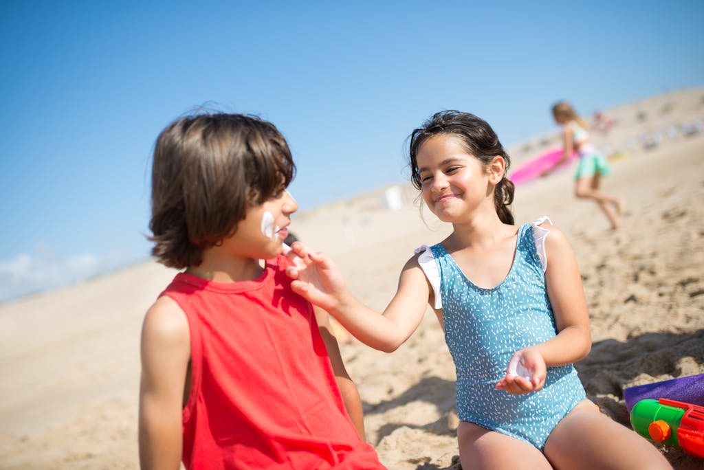 Children playing and applying sunscreen on a sunny beach in Portugal. Perfect summer vacation scene.