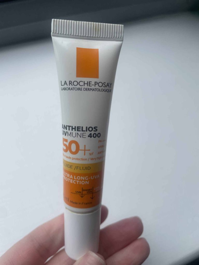 Me holding a 15ml tube of La Roche-Posay Anthelios UVMune 400 Invisible Fluid SPF 50+ sunscreen against a plain white background.