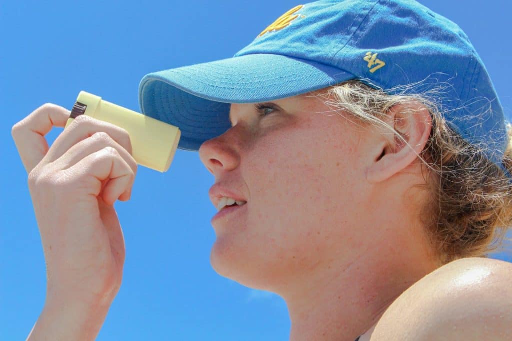 a woman wearing a blue hat looking through a magnifying glass