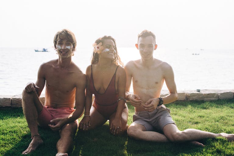 A group of young adults enjoying sunny day at the beach, wearing sunscreen.