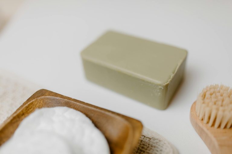 Close-up of a natural soap bar with a wooden brush and cotton pads for skincare.