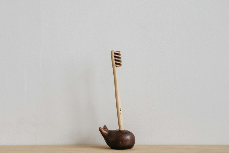 Wooden toothbrush displayed in a minimalist holder, promoting zero waste and dental hygiene.